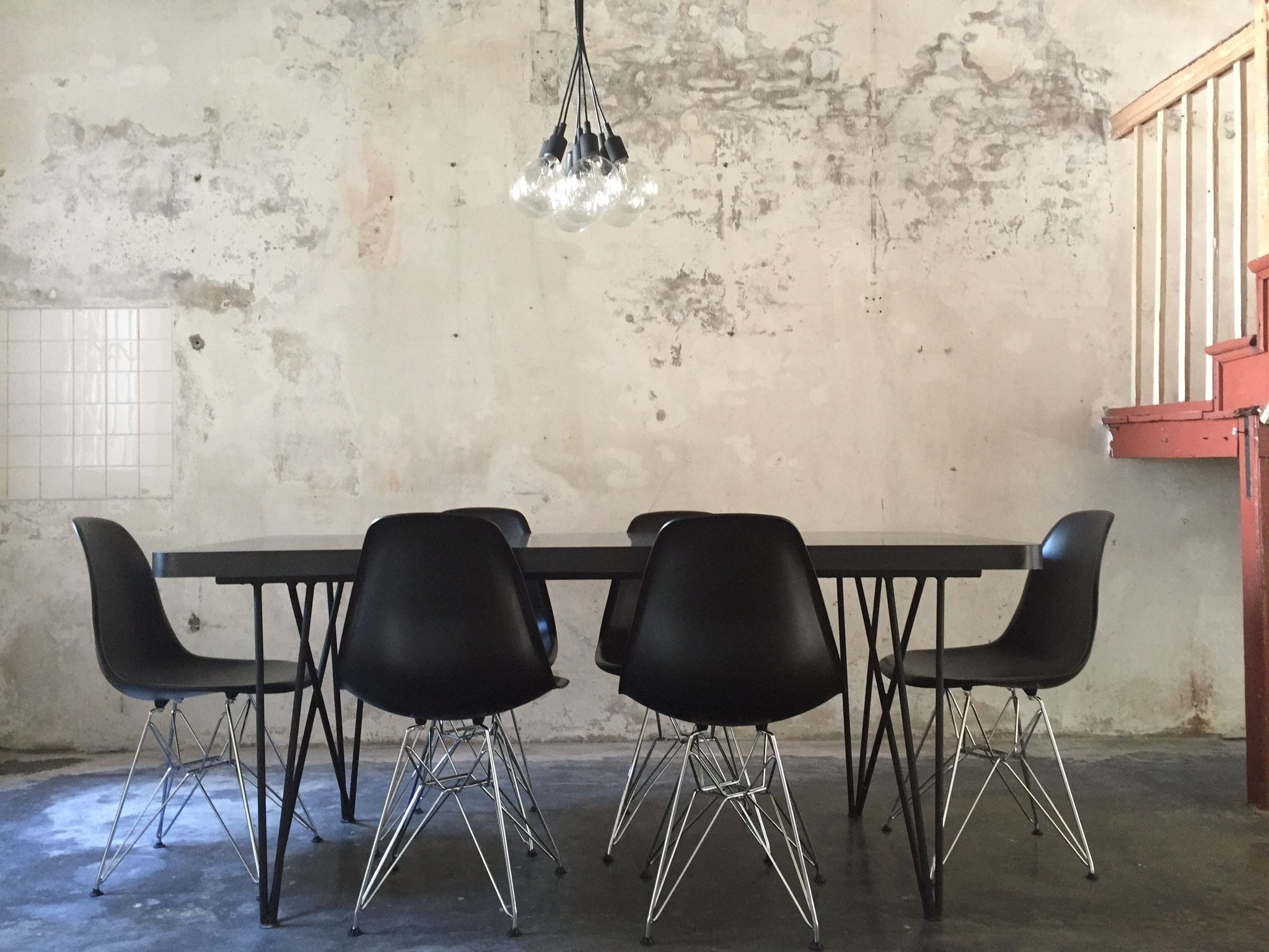 Un salón de conferencias con una mesa larga y cuatro sillas negras con patas de metal.