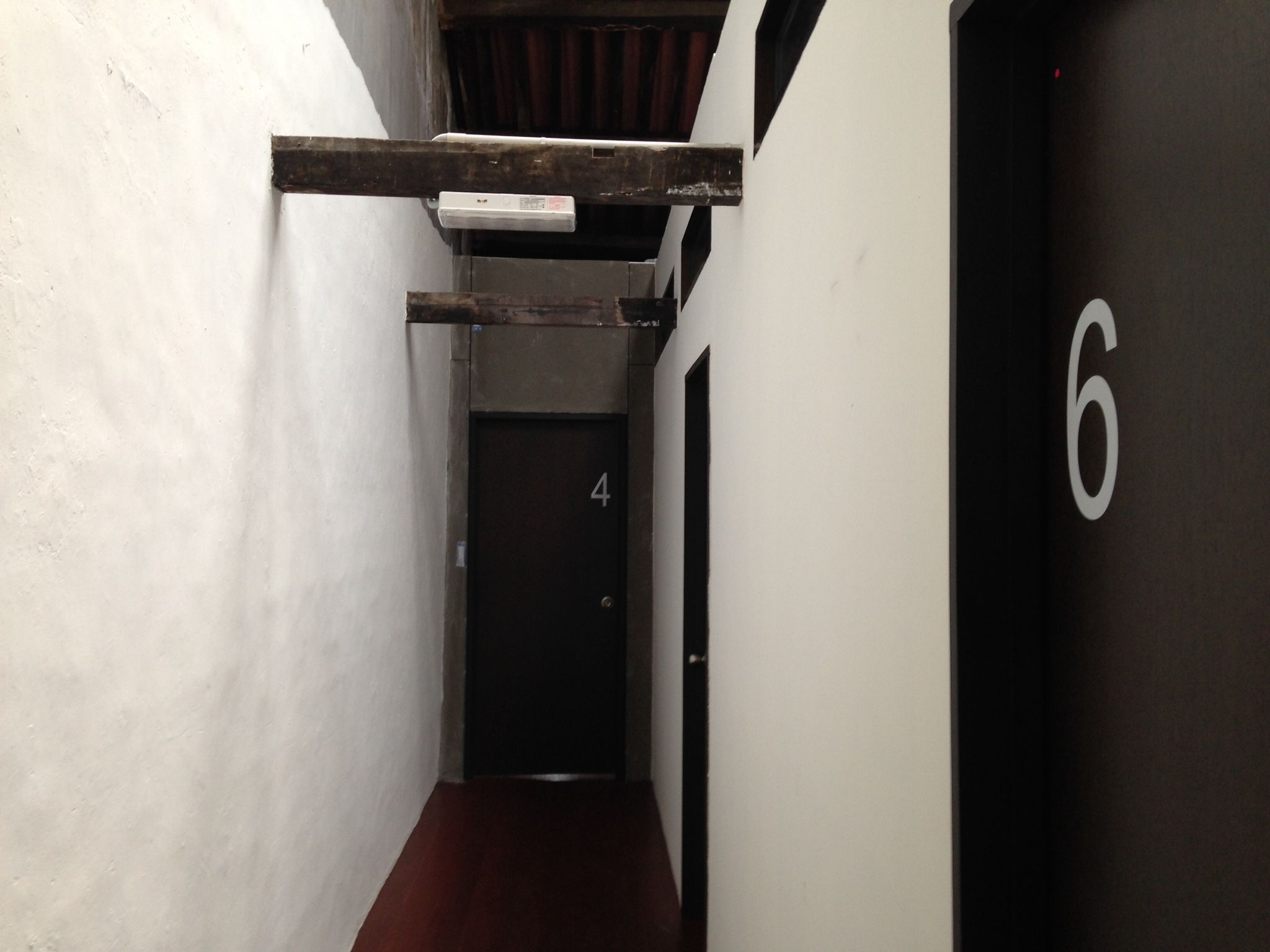 A narrow hallway with a wooden beam overhead, a door labeled '4', and a wall with the number '6'.