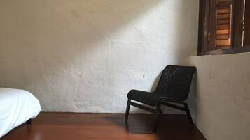 A room with a wooden floor, a white wall, and a black chair.