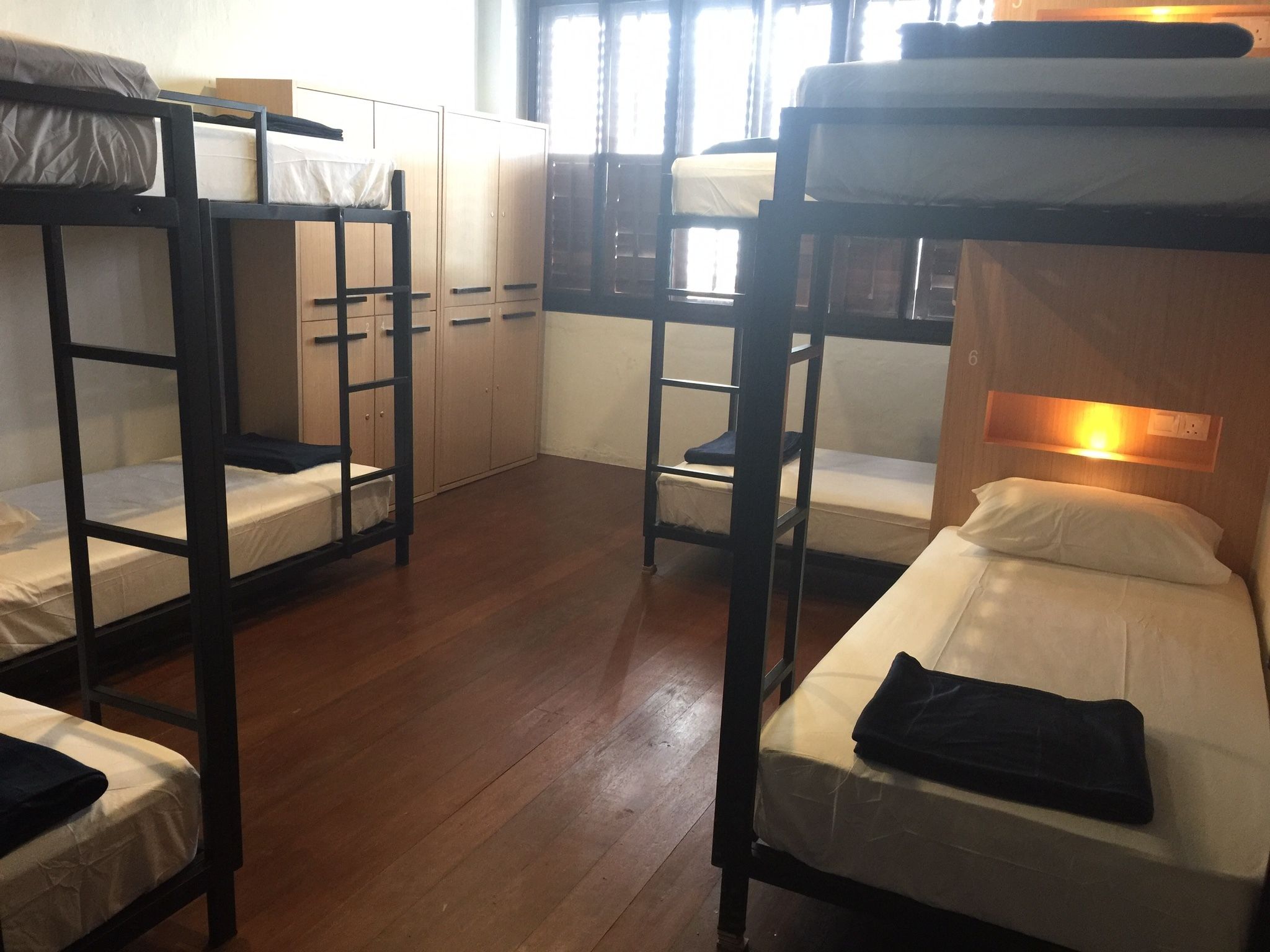 Ein Schlafsaalzimmer mit Etagenbetten, Holzboden und einem Fenster mit Vorhängen.
