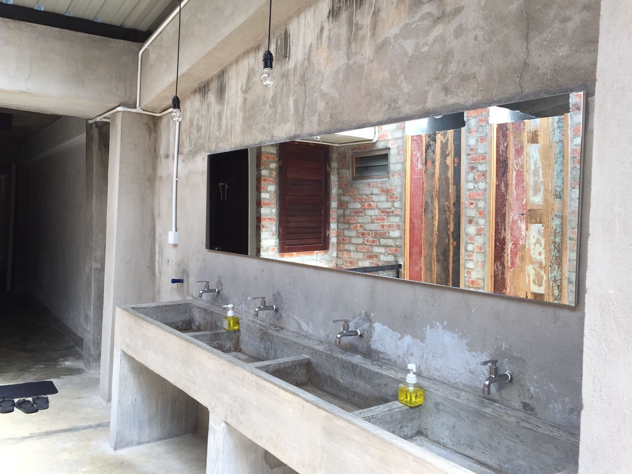 A bathroom with a large mirror, three sinks, and a wooden door.