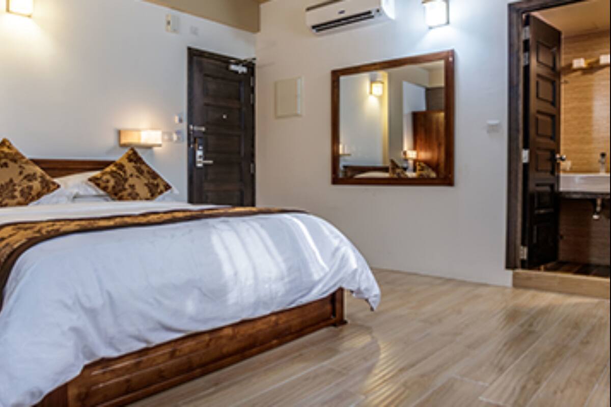 Habitación de hotel con una cama grande, cabecero de madera y un espejo en la pared.