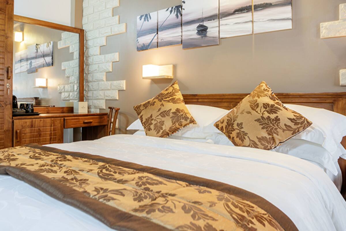 Habitación de hotel con cama, escritorio y espejo.