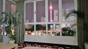 A hotel room with a large window offering a city view, including a prominent tower. - Balkoni Hijau at Casa Mutiara KL (Kuala Lumpur)