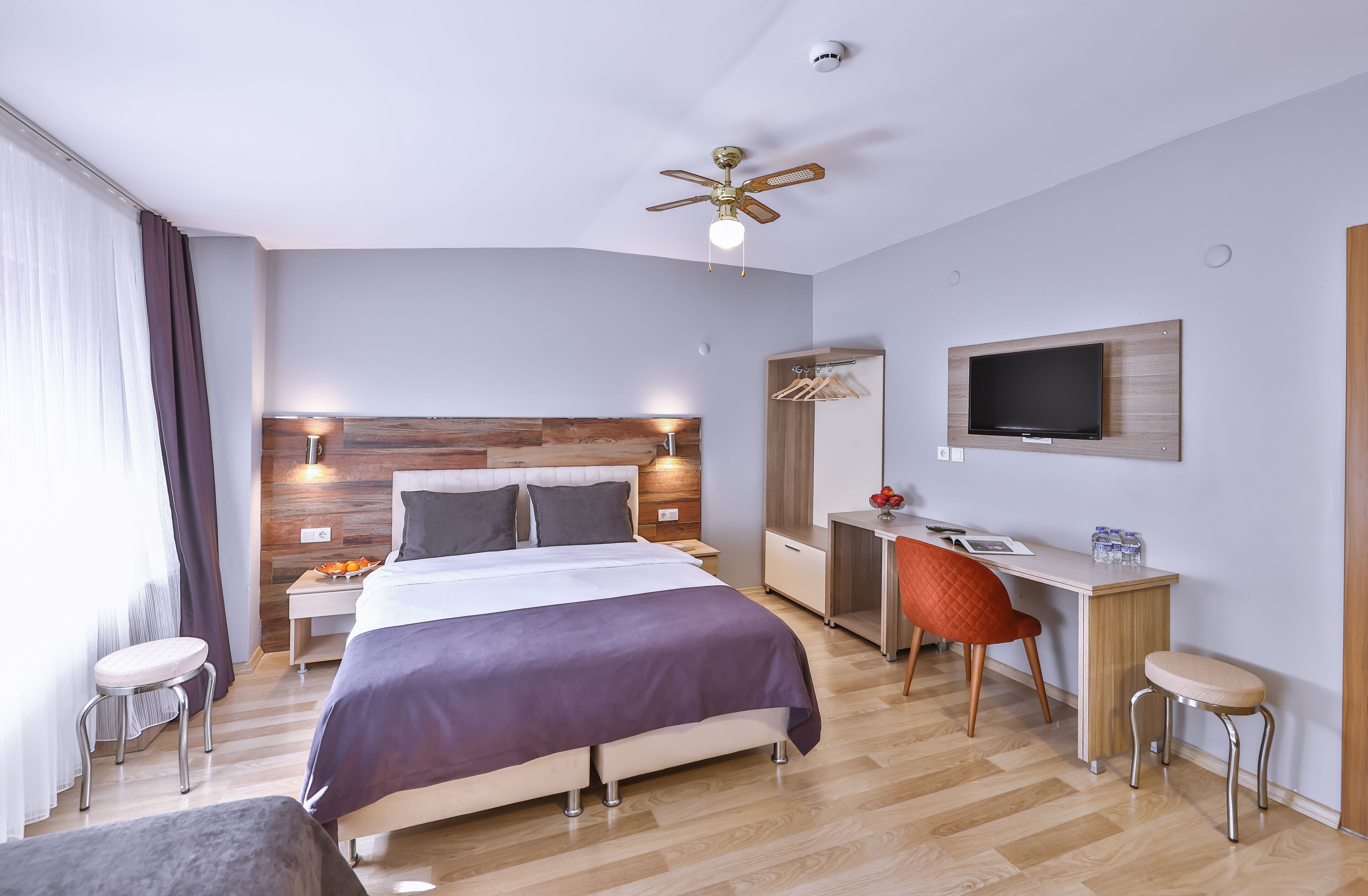 Una habitación de hotel moderna con cama, escritorio, silla y televisor.