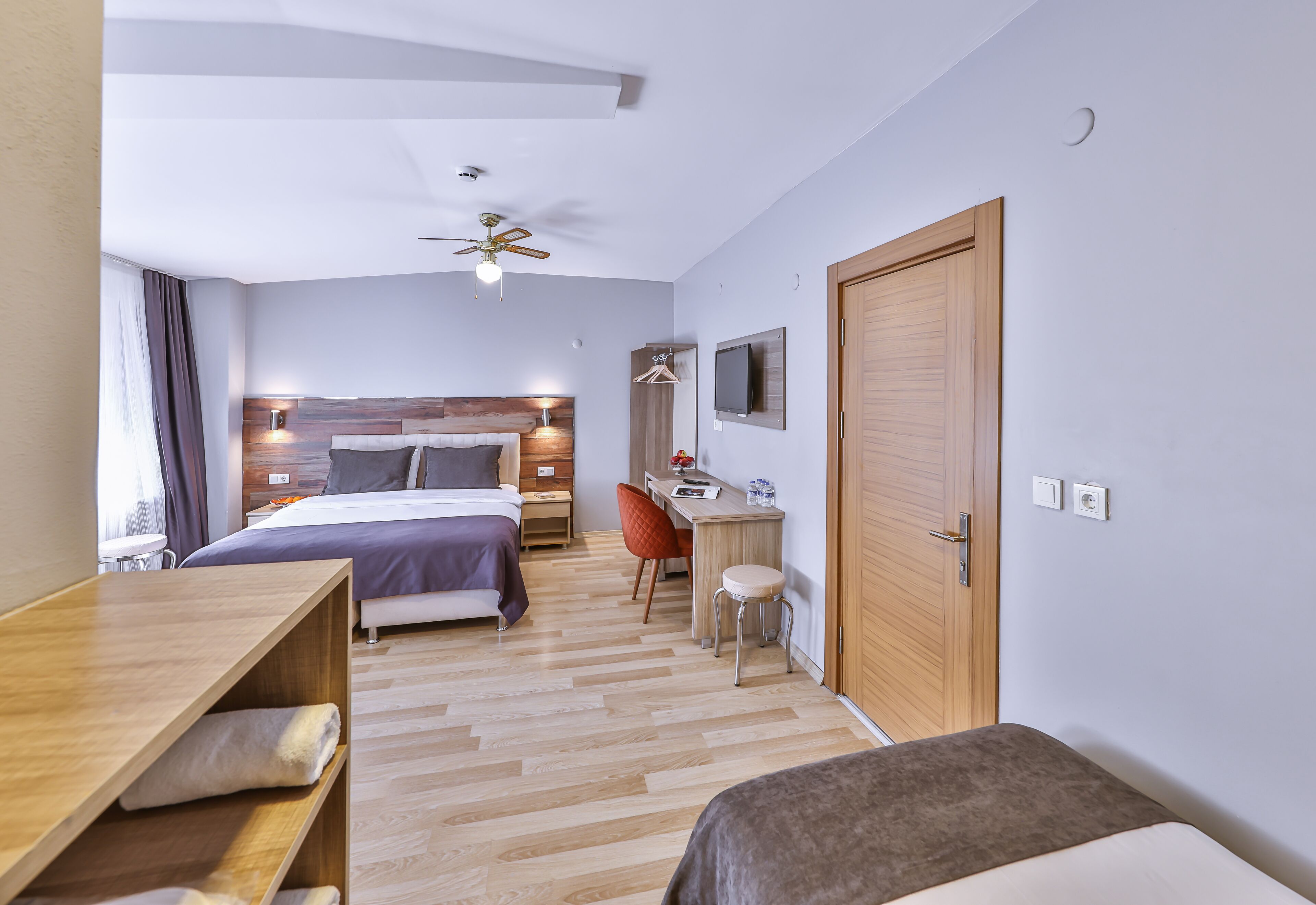 A hotel room with a bed, desk, chair, and a TV.