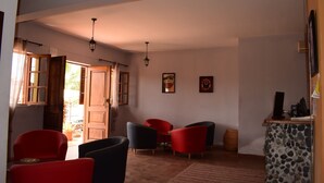 Amplia sala de estar con una gran puerta de madera, una silla roja y negra, una mesita y una encimera de piedra.