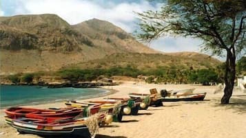 Una spiaggia con barche ormeggiate e una montagna sullo sfondo.