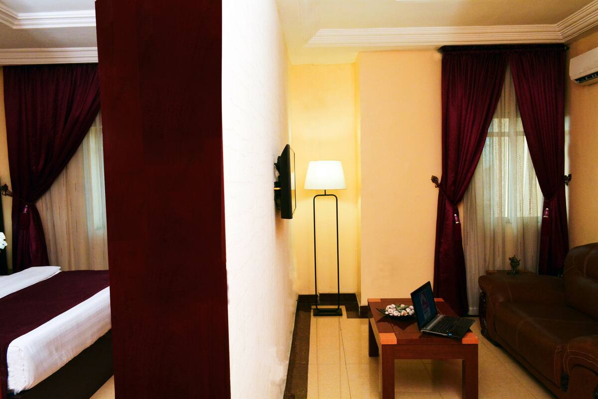 Une chambre d’hôtel avec un lit, un bureau avec un ordinateur portable, un canapé et une lampe.