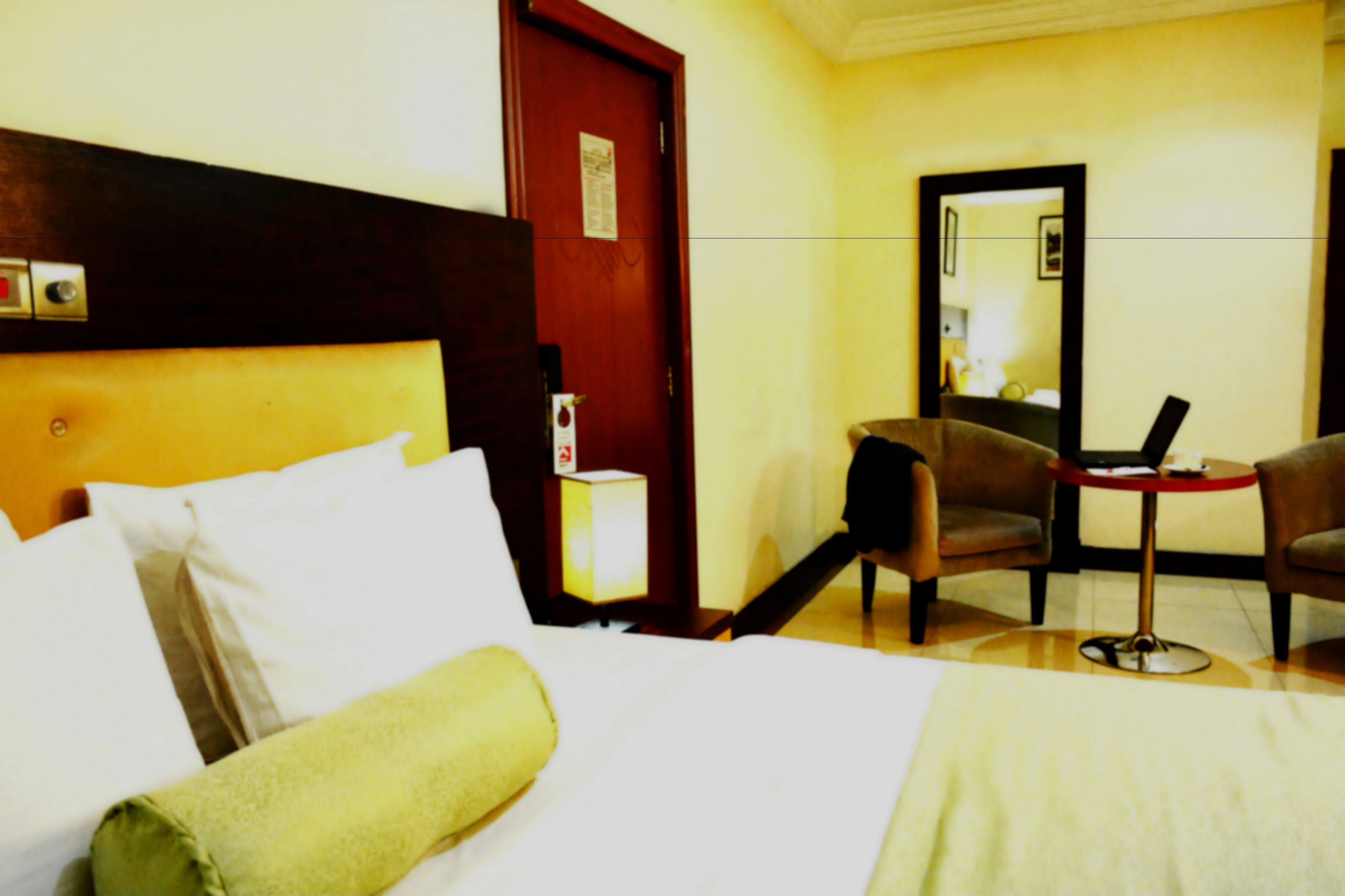 Una habitación de hotel con cama, escritorio, dos sillas, espejo y una mesita.