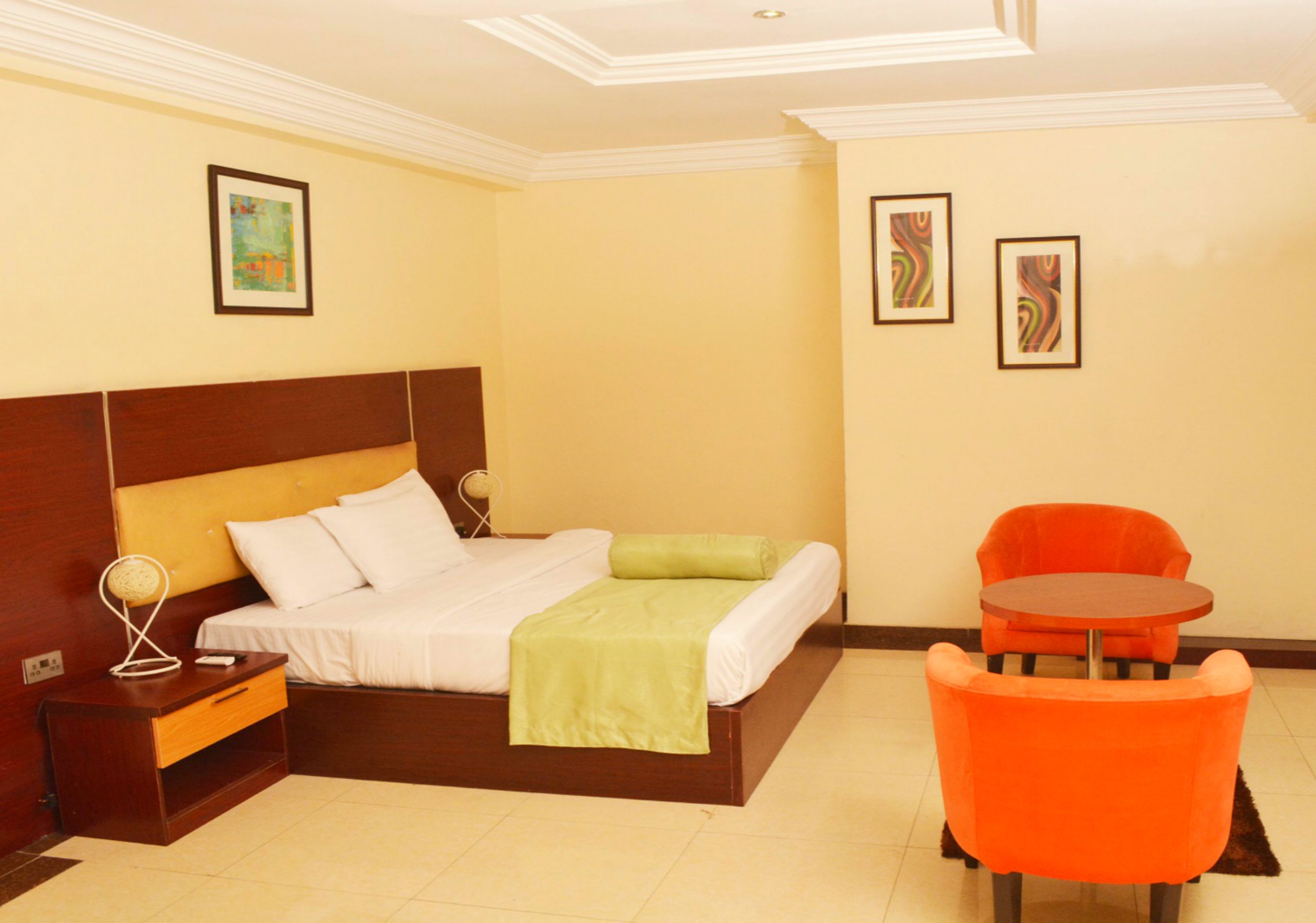 A hotel room with a bed, a nightstand, a chair, and a small table.