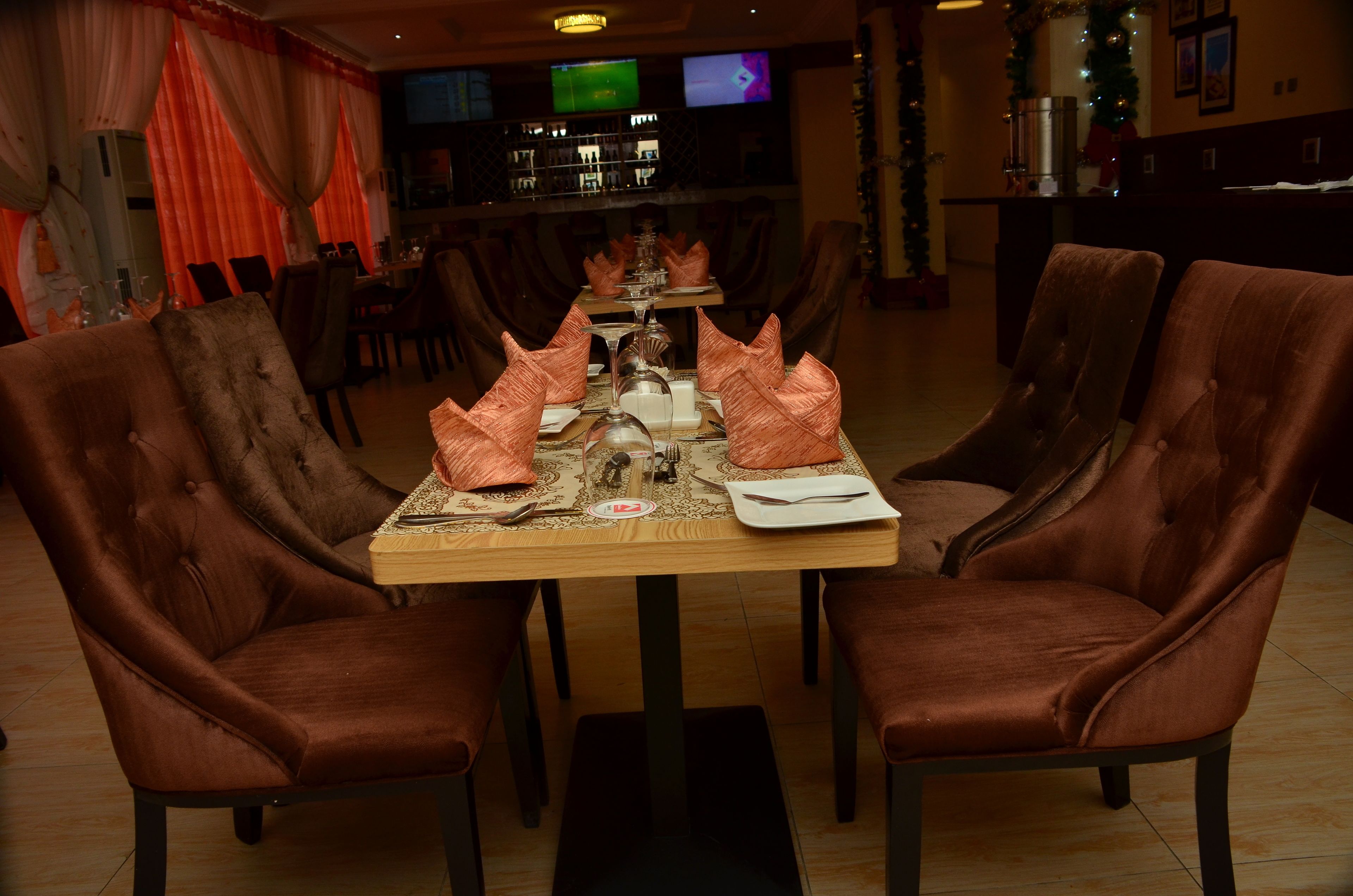 A dining area with a long table set for four, surrounded by upholstered chairs.
