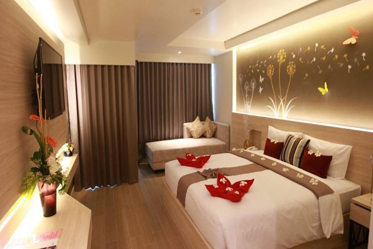 Une chambre d’hôtel avec un grand lit, un lit plus petit, un bureau et une télévision.