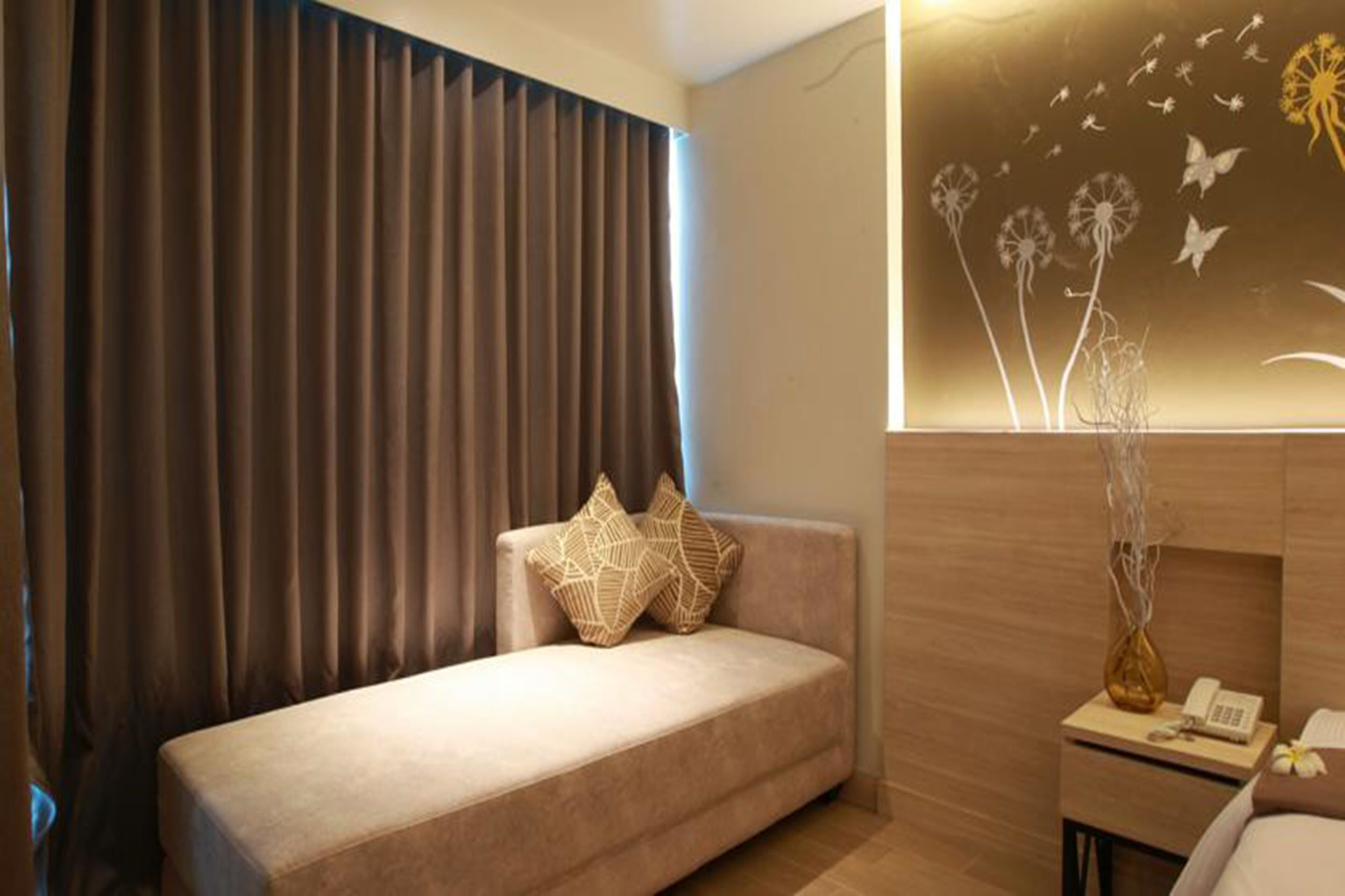 Een moderne hotelkamer met een bank, een nachtkastje met een telefoon, en een kunstwerk aan de muur.