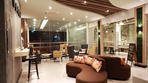 A modern hotel lobby with a seating area, a reception desk, and a dining area. - Levana Pattaya Hotel (Pattaya)