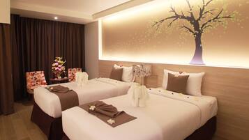 A hotel room with two beds, a nightstand with a vase of flowers, and a wall-mounted tree decal.