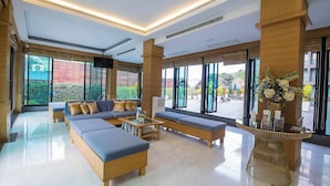 A modern hotel lobby with a large sofa, a coffee table, and a reception desk.