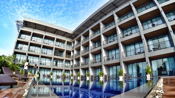 A modern hotel with a rooftop infinity pool, multiple balconies, and outdoor seating areas.
