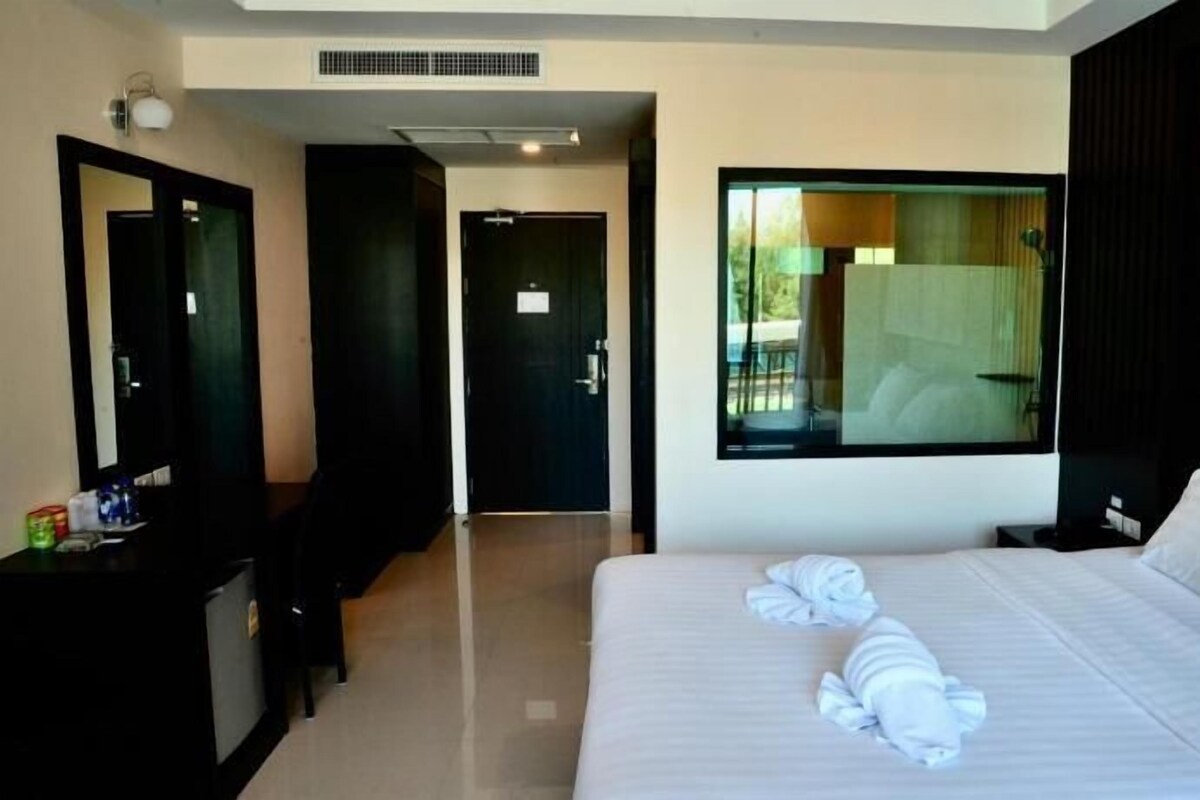 Una camera d'albergo con un letto grande, una scrivania, uno specchio e una finestra vista all'esterno.