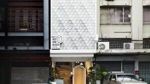 A modern hostel with a geometric facade, a visible entrance, and a parked car. - Bed One Block Hostel (Bangkok)