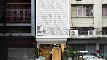 Un hostal moderno con fachada geométrica, una entrada visible y un coche estacionado.