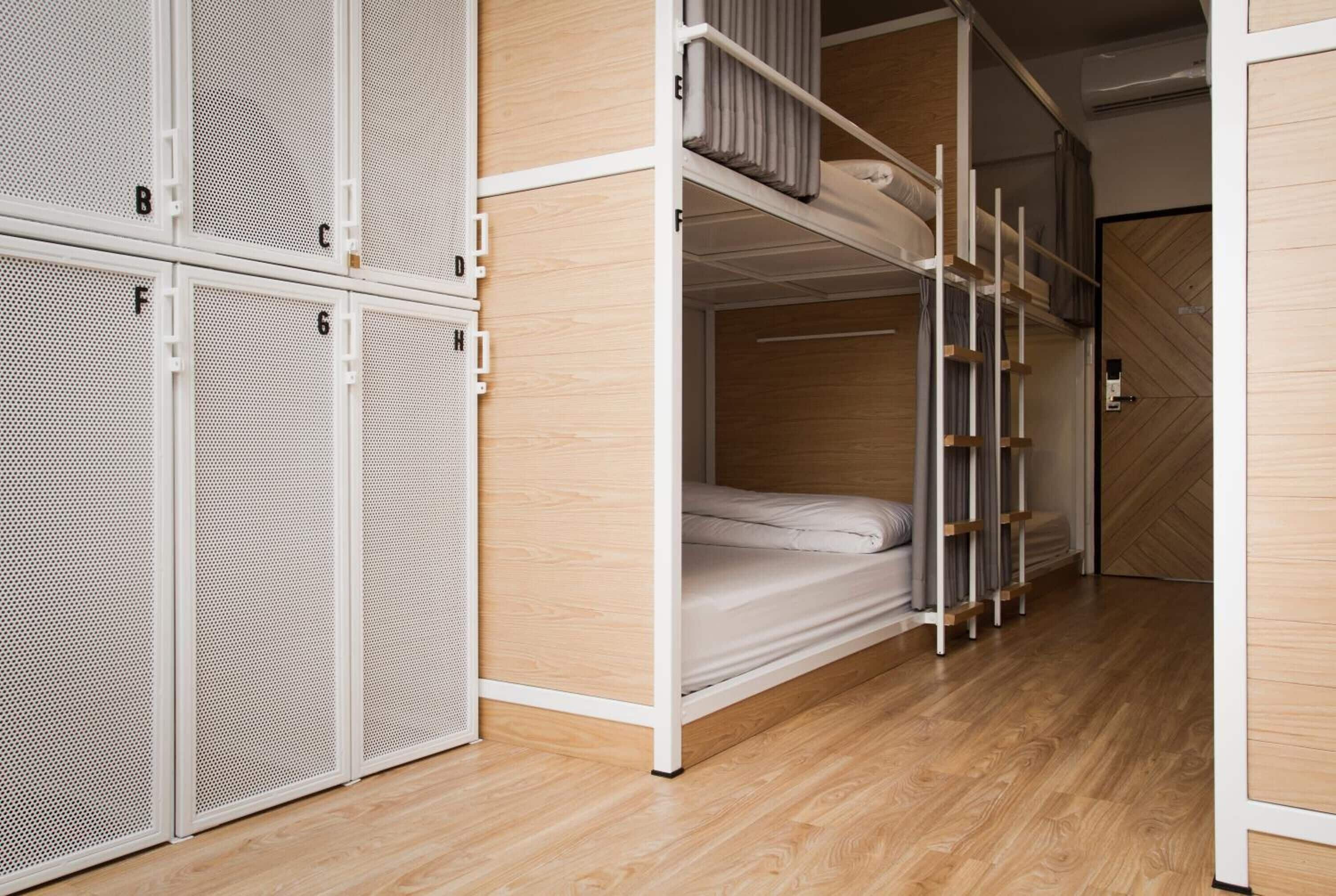 A bunk bed room with a wooden floor and white metal lockers.