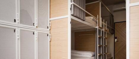 A bunk bed room with a wooden floor and white metal lockers.