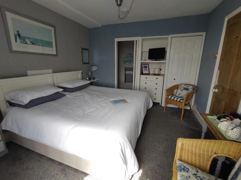 A bedroom with a bed, a chair, a television, and a wardrobe.