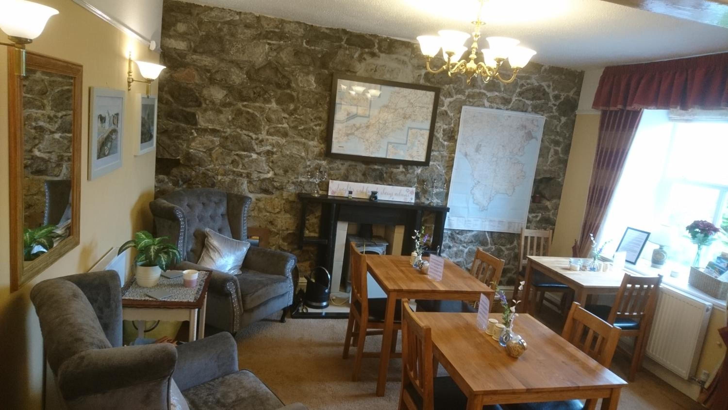 Una sala de estar acogedora con pared de piedra, chimenea, mesa de comedor y asientos cómodos.