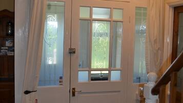 A white double door with frosted glass panels, a fire extinguisher on the left, and a wooden staircase to the right.