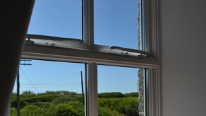 Ein Zimmer mit einem Bett und einem großen Fenster mit Blick auf Grünflächen.