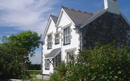 A two-story stone house with a white facade and a tiled roof.