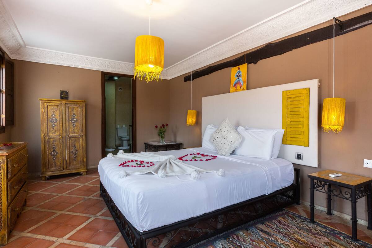 A bedroom with a bed, wooden wardrobe, and a nightstand.