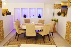 Een eethoek met een ronde tafel, zes stoelen en decoratieve vazen.