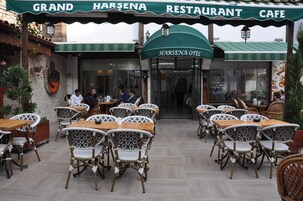 Un área de estar al aire libre con sillas y mesas de mimbre en el Restaurante Café Grand Harsena.