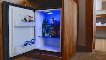 A compact refrigerator with a wooden exterior, containing various beverages and condiments.