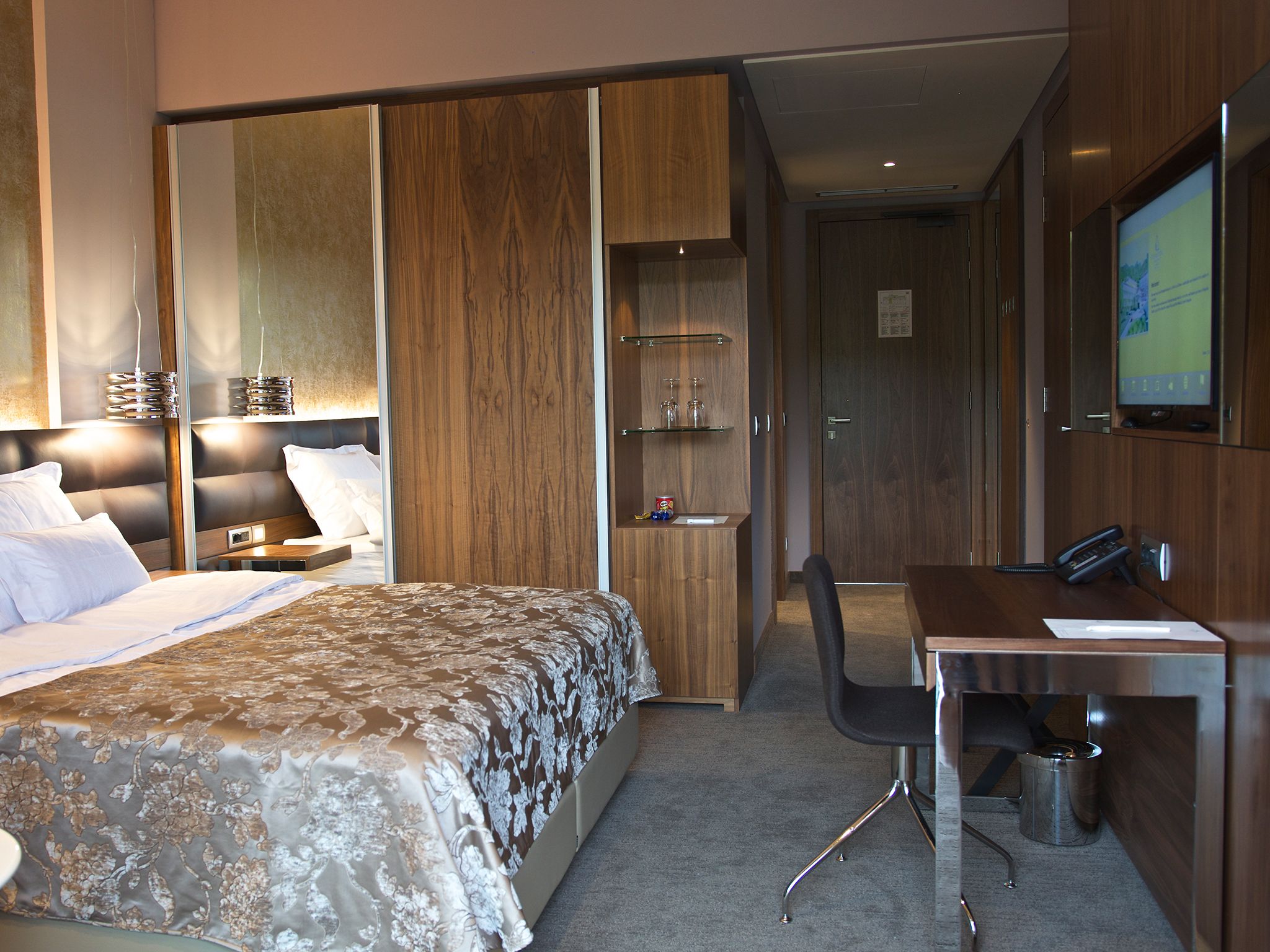Una habitación de hotel moderna con una cama grande, un escritorio y un televisor.