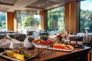 A buffet table with a variety of fruits and vegetables, a white vase with dried flowers, and a glass bowl with berries. - Atlantida Boutique Hotel (Rogaska Slatina)