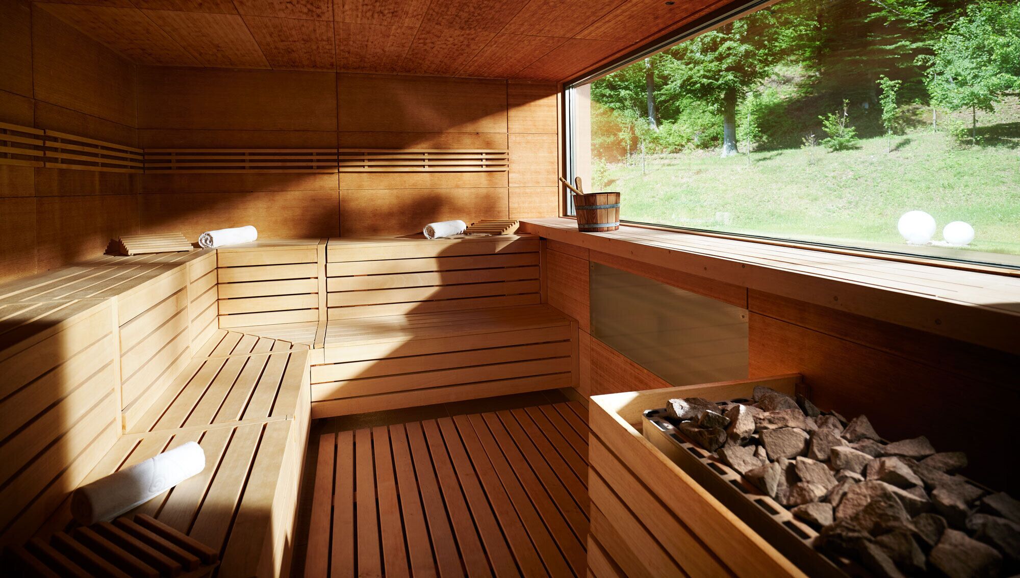 Una sauna con bancos de madera y ventanal con vistas a una zona verde.