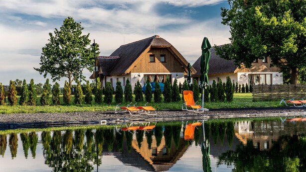 Una propiedad frente al lago con una amplia casa de madera, una piscina y sillones reclinables anaranjados.