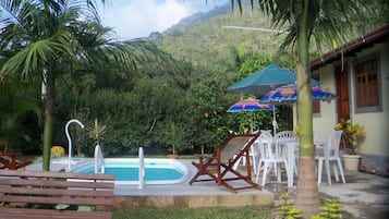 Una piscina al aire libre, sombrillas, sillones reclinables de piscina