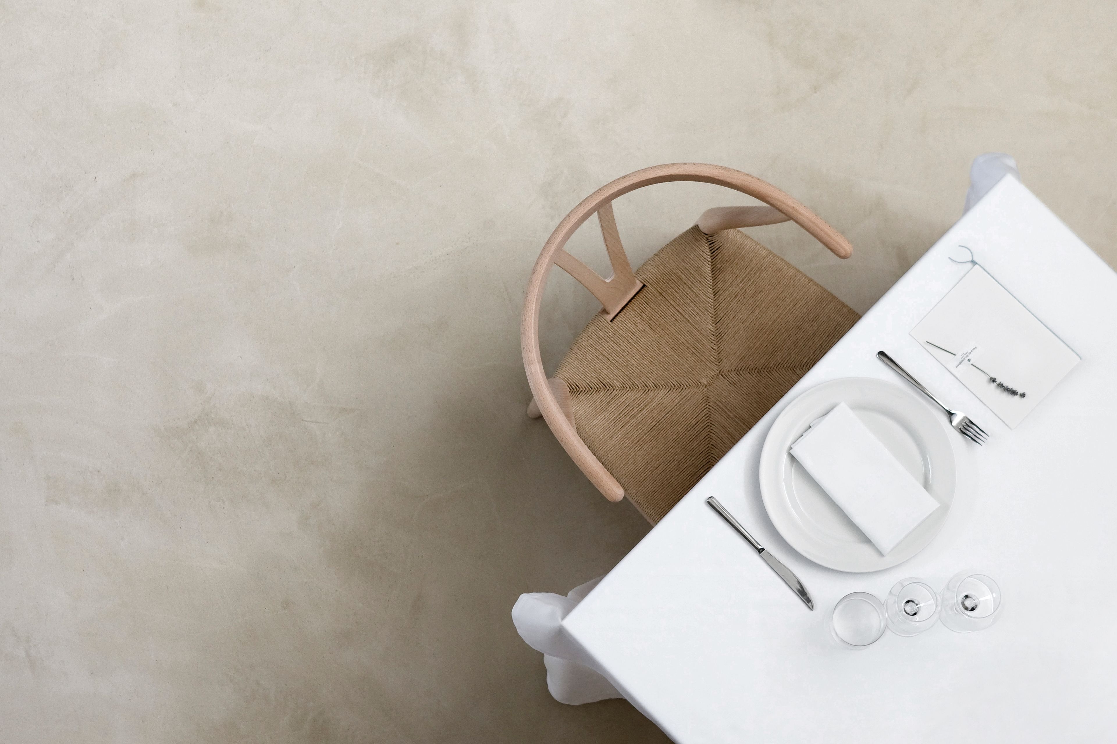 Vue d’ensemble d’une table à manger, avec une nappe blanche, une chaise en osier et un menu.