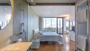 Un dormitorio moderno con una cama grande, un baño con bañera y vistas al exterior.