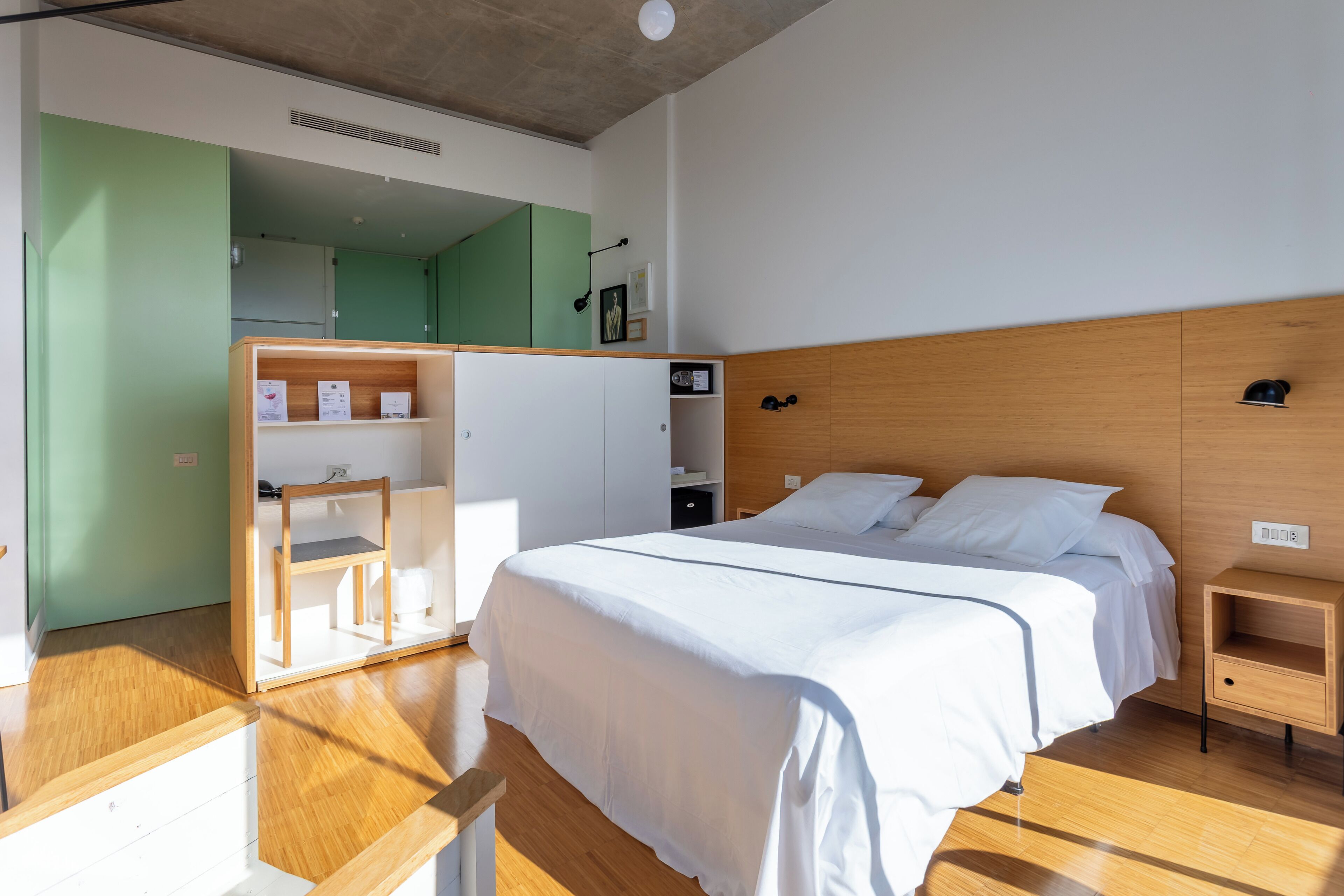 Ein modernes Schlafzimmer mit einem großen Bett, Nachttischen aus Holz, einem Einbauschrank und einem Spiegel.