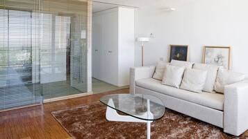Una sala moderna con una mesa de centro de vidrio, un sofá blanco y una alfombra marrón.
