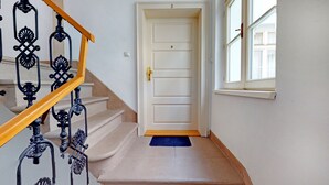 A staircase with ornate black metal railings and a wooden handrail leading to a white door with a brass handle.