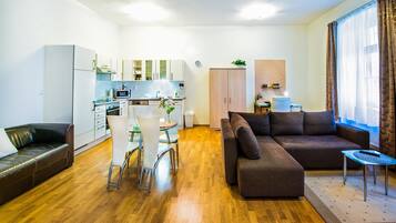 Un espacio habitable compacto con kitchenette, una zona de comedor, un sofá y una pequeña mesa con un control remoto.