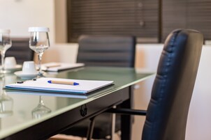 Una mesa de conferencias con un cuaderno, bolígrafo y una copa de vino.