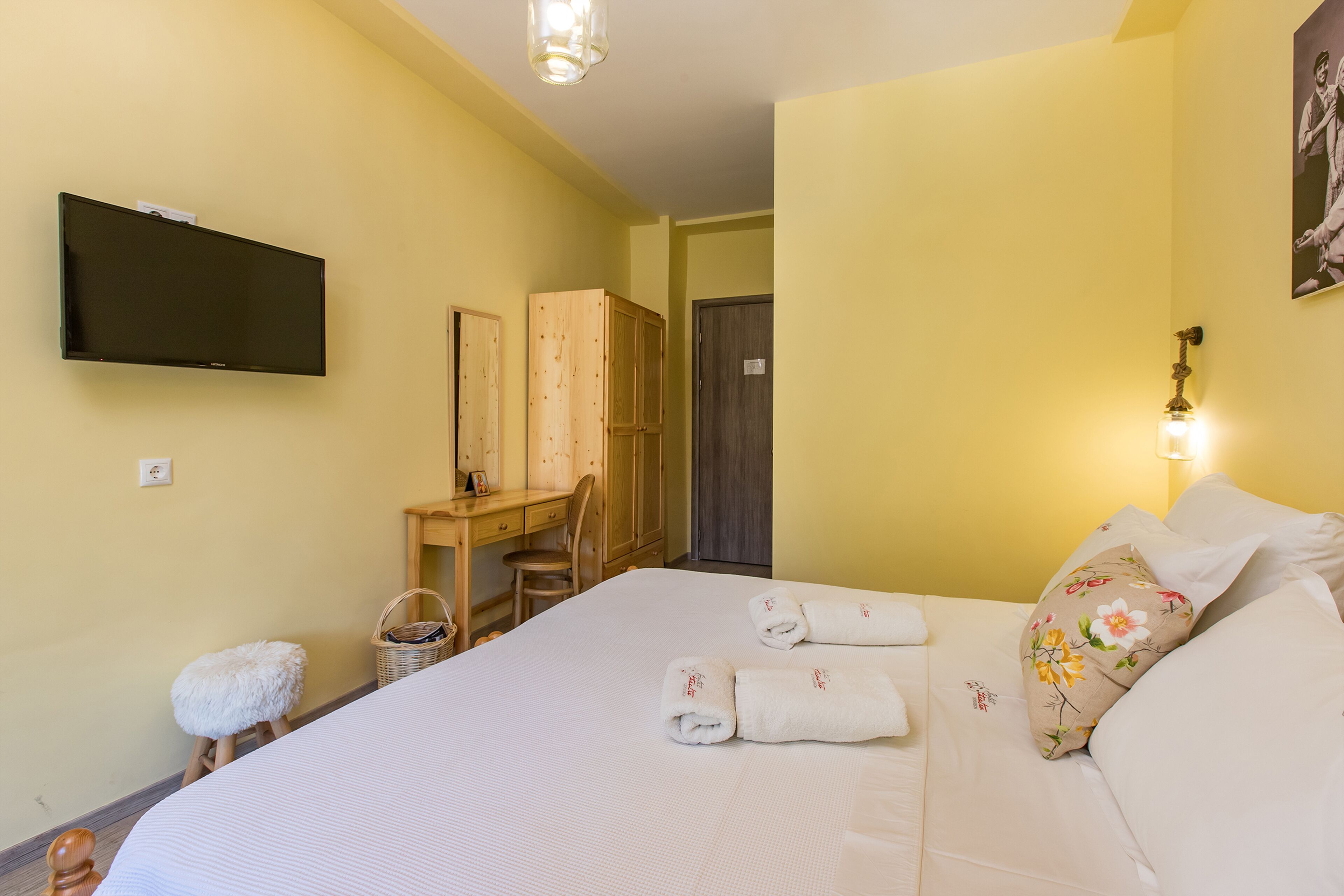 Habitación de hotel con cama, escritorio, silla, televisión y puerta.
