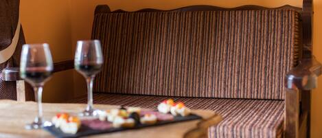 A wooden table with two wine glasses and a plate of appetizers.